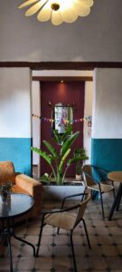 Sala bohémia con sofá naranja y plantas colgantes en Somos Legados Cali