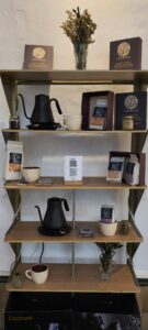 Estantería con kettles, tazas y bolsas de café Legados y código QR del menú